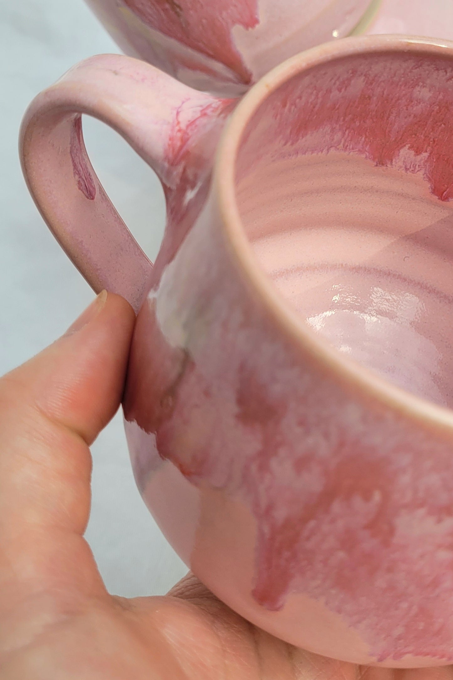 Handgemachte Steinzeugtasse Bloom, 350 ml, glänzende rosa Glasur mit dunklen Akzenten.