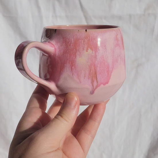 Handgemachte Steinzeugtasse Bloom, 350 ml, glänzende rosa Glasur mit dunklen Akzenten.