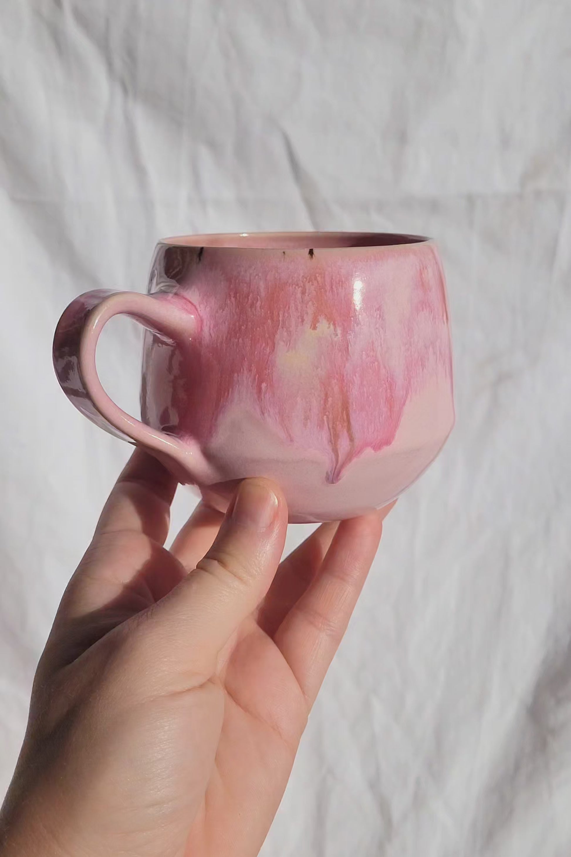 Handgemachte Steinzeugtasse Bloom, 350 ml, glänzende rosa Glasur mit dunklen Akzenten.